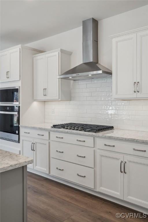 kitchen featuring white cabinets, light stone countertops, wall chimney exhaust hood, and appliances with stainless steel finishes