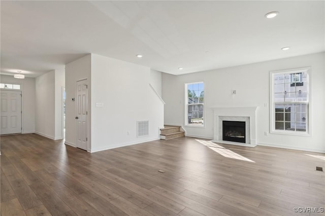 unfurnished living room featuring wood-type flooring and a high end fireplace