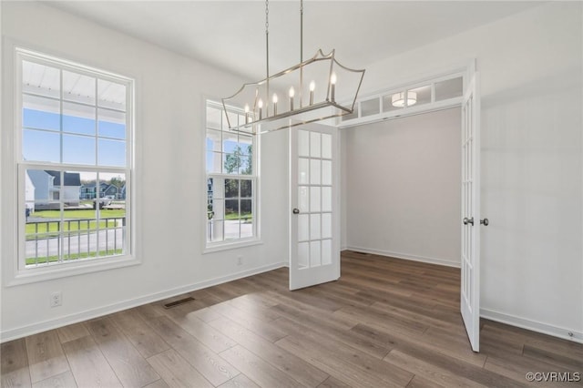 unfurnished dining area featuring dark hardwood / wood-style flooring and an inviting chandelier