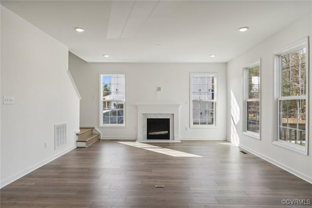 unfurnished living room with a premium fireplace, dark wood-type flooring, and a wealth of natural light