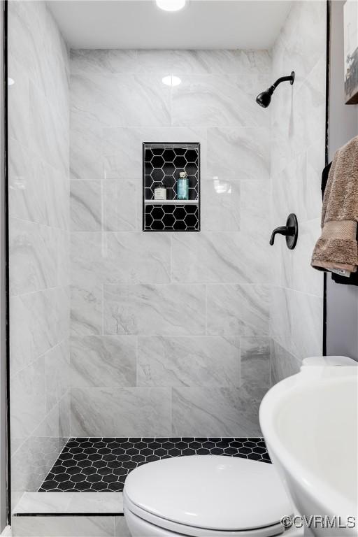 bathroom with tiled shower and toilet