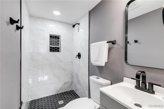 bathroom featuring tiled shower, vanity, and toilet