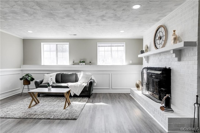 living room with hardwood / wood-style flooring, a fireplace, ornamental molding, and a textured ceiling