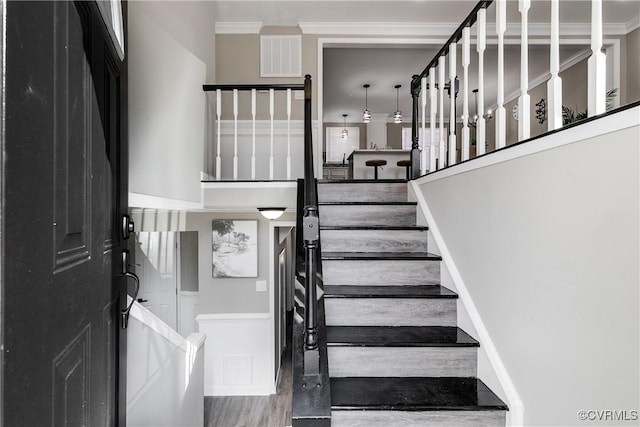 stairway featuring ornamental molding and hardwood / wood-style floors