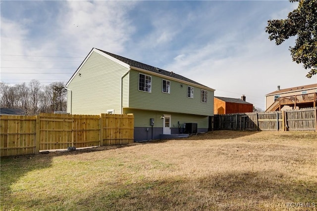 back of property with central AC and a lawn