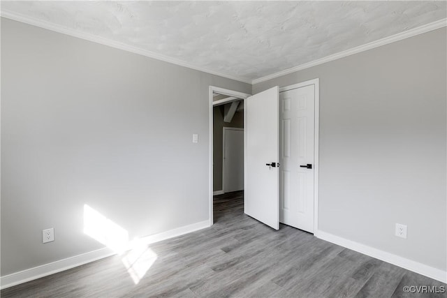 unfurnished bedroom with crown molding, wood-type flooring, and a closet