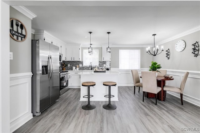 kitchen featuring white cabinetry, crown molding, stainless steel appliances, and a center island