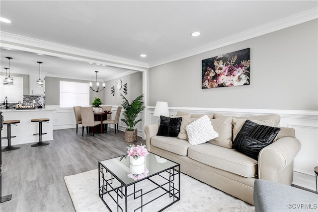 living room featuring crown molding, a chandelier, and light hardwood / wood-style floors