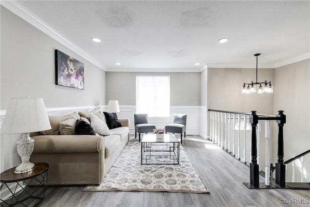 living room featuring wood-type flooring, ornamental molding, and a notable chandelier