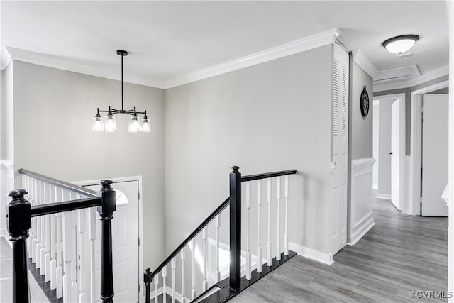 staircase featuring ornamental molding, a chandelier, and wood-type flooring