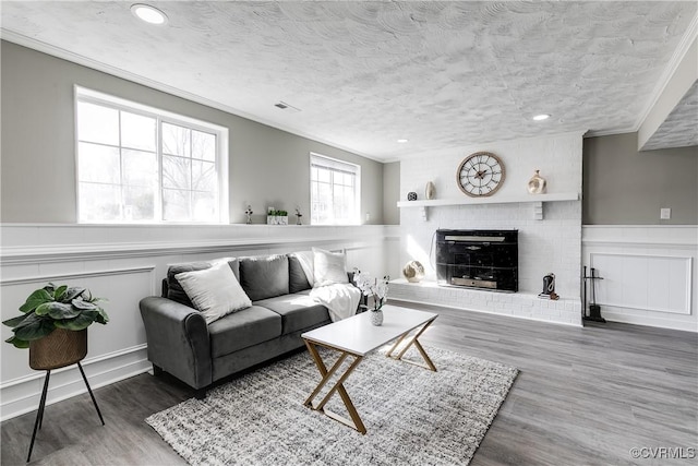 living room with hardwood / wood-style flooring, crown molding, a textured ceiling, and a fireplace