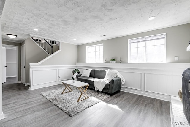 living area featuring crown molding, wood-type flooring, and a textured ceiling