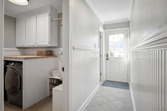 washroom with ornamental molding, light tile patterned floors, washer / clothes dryer, and cabinets