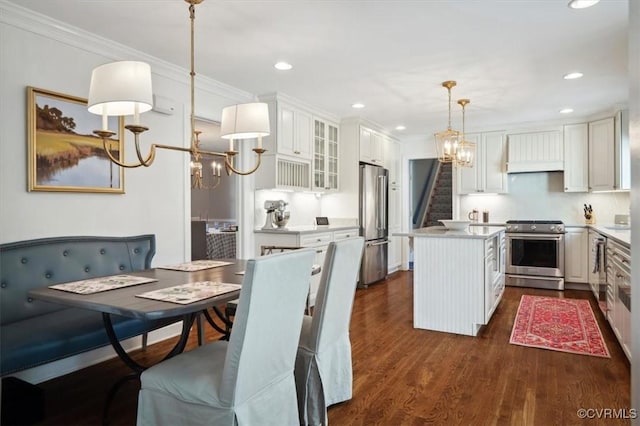 kitchen with white cabinets, premium appliances, pendant lighting, and a center island