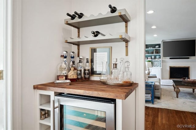 bar featuring built in shelves, wine cooler, dark hardwood / wood-style flooring, and butcher block counters