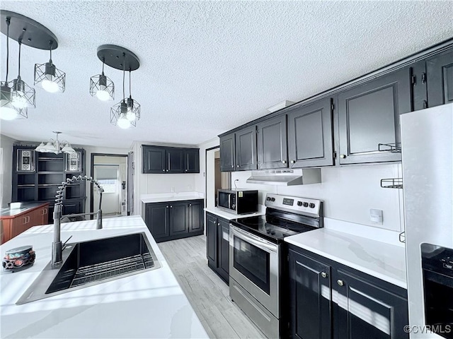 kitchen featuring sink, appliances with stainless steel finishes, light hardwood / wood-style floors, a textured ceiling, and decorative light fixtures