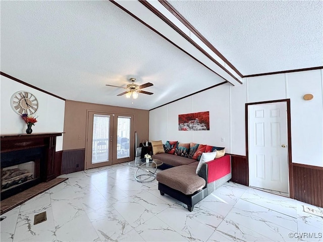 living room featuring vaulted ceiling with beams, ornamental molding, a textured ceiling, french doors, and wood walls