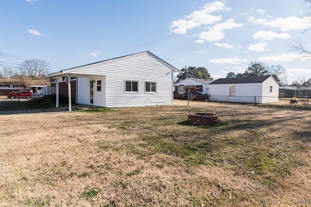 rear view of property with a lawn and an outdoor fire pit