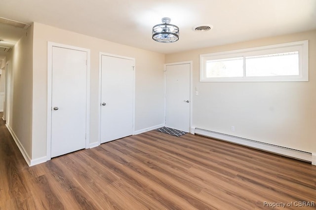 unfurnished bedroom featuring a baseboard radiator and dark hardwood / wood-style flooring