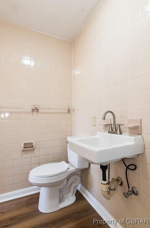 bathroom featuring sink, hardwood / wood-style floors, tile walls, and toilet