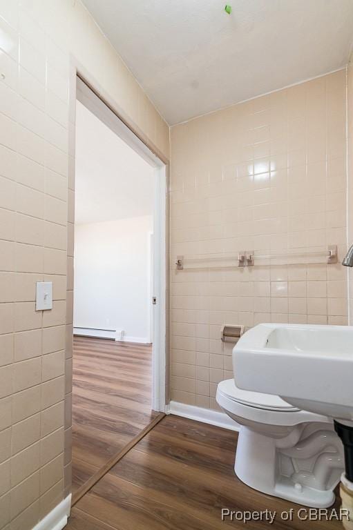 bathroom featuring wood-type flooring, toilet, tile walls, and a baseboard heating unit