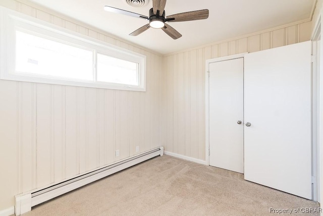 carpeted spare room with ceiling fan and a baseboard heating unit