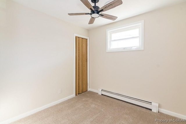 carpeted spare room with a baseboard radiator and ceiling fan