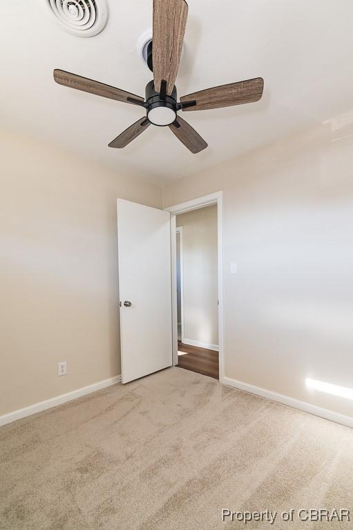 carpeted spare room featuring ceiling fan