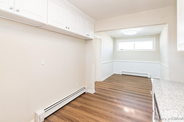 clothes washing area with a baseboard radiator and wood-type flooring