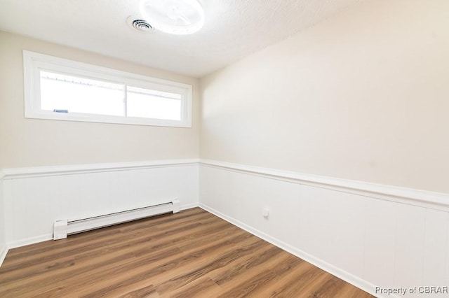 unfurnished room with a baseboard radiator and hardwood / wood-style floors