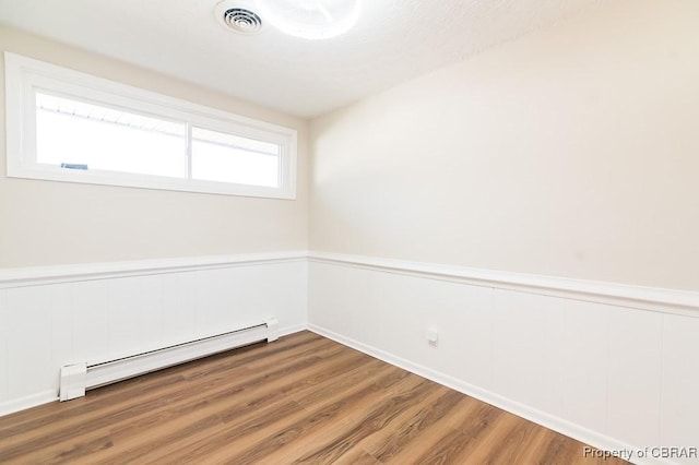 empty room featuring hardwood / wood-style floors and a baseboard radiator