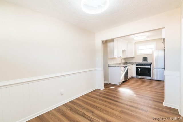 kitchen featuring appliances with stainless steel finishes, sink, hardwood / wood-style floors, and white cabinets