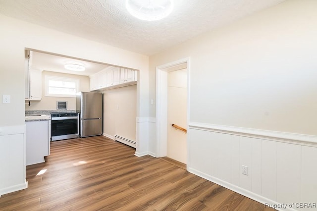 kitchen featuring a baseboard heating unit, hardwood / wood-style flooring, white cabinets, and appliances with stainless steel finishes