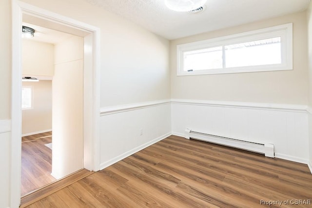 spare room featuring hardwood / wood-style flooring and a baseboard heating unit