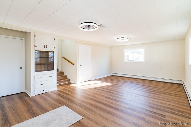 empty room featuring baseboard heating and hardwood / wood-style floors