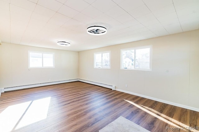 spare room featuring a baseboard radiator, wood-type flooring, and a wealth of natural light