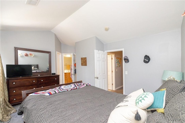 carpeted bedroom with connected bathroom and vaulted ceiling