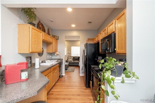 kitchen featuring sink, light brown cabinetry, light hardwood / wood-style floors, and black appliances