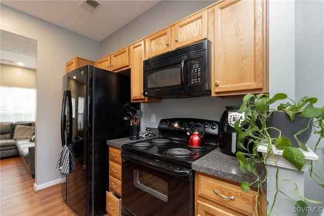 kitchen with light hardwood / wood-style floors, light brown cabinets, and black appliances