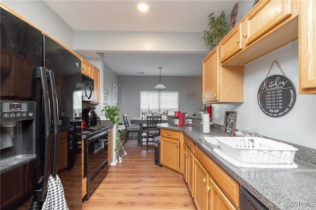 kitchen with pendant lighting, light brown cabinetry, black appliances, and light hardwood / wood-style floors