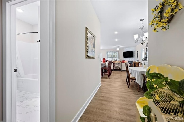 hall with light hardwood / wood-style floors and a notable chandelier