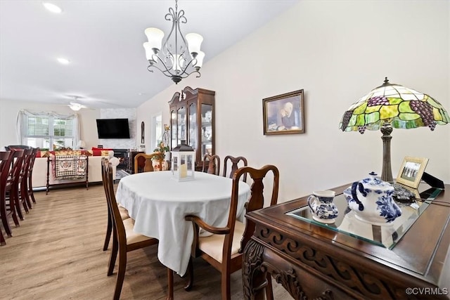 dining space with ceiling fan with notable chandelier and light wood-type flooring