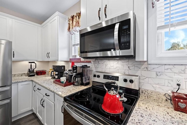 kitchen featuring white cabinetry, light stone counters, tasteful backsplash, and stainless steel appliances