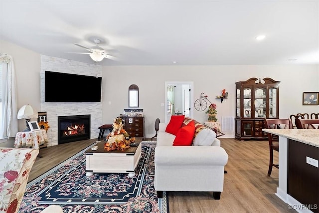 living room featuring a fireplace, light hardwood / wood-style floors, and ceiling fan