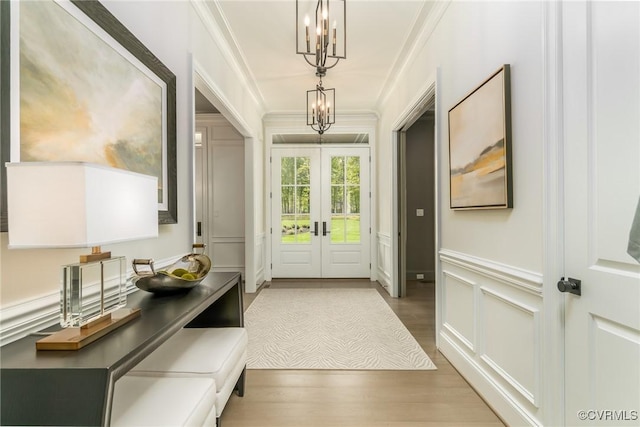 doorway with hardwood / wood-style flooring, ornamental molding, a chandelier, and french doors