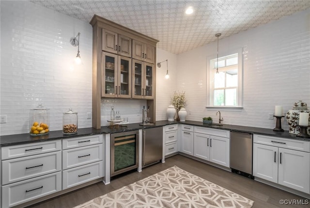 kitchen with sink, refrigerator, white cabinetry, decorative light fixtures, and beverage cooler