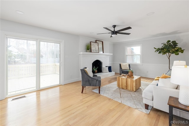 living room featuring a fireplace, light hardwood / wood-style flooring, and ceiling fan