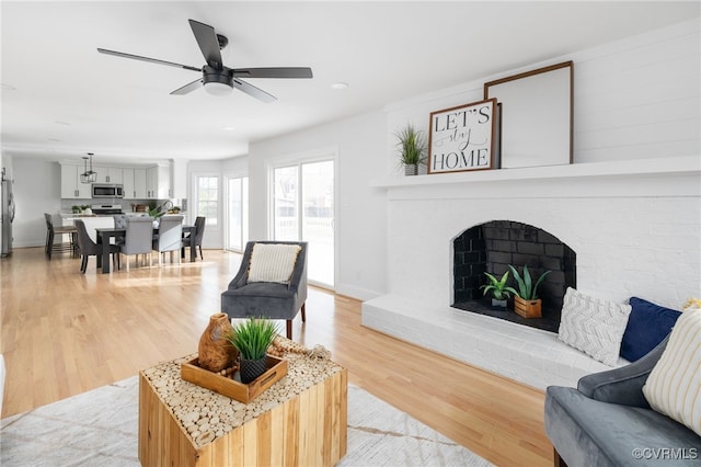 living room with a fireplace, wood-type flooring, and ceiling fan