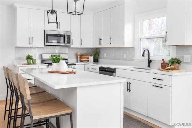 kitchen featuring a breakfast bar, pendant lighting, white cabinets, a center island, and stainless steel appliances