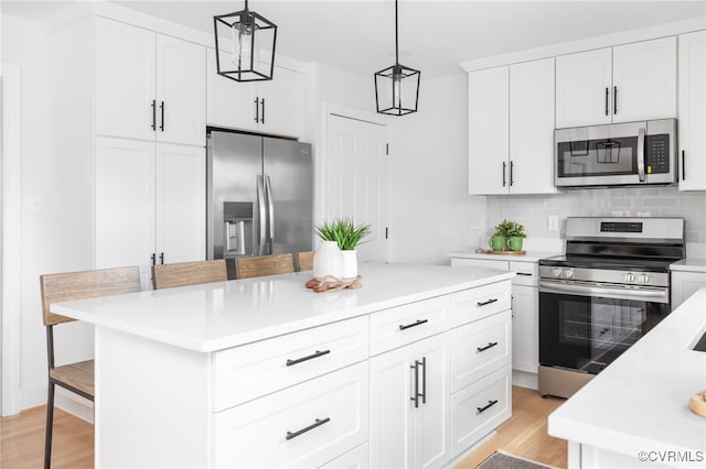 kitchen featuring hanging light fixtures, a breakfast bar area, white cabinets, and appliances with stainless steel finishes